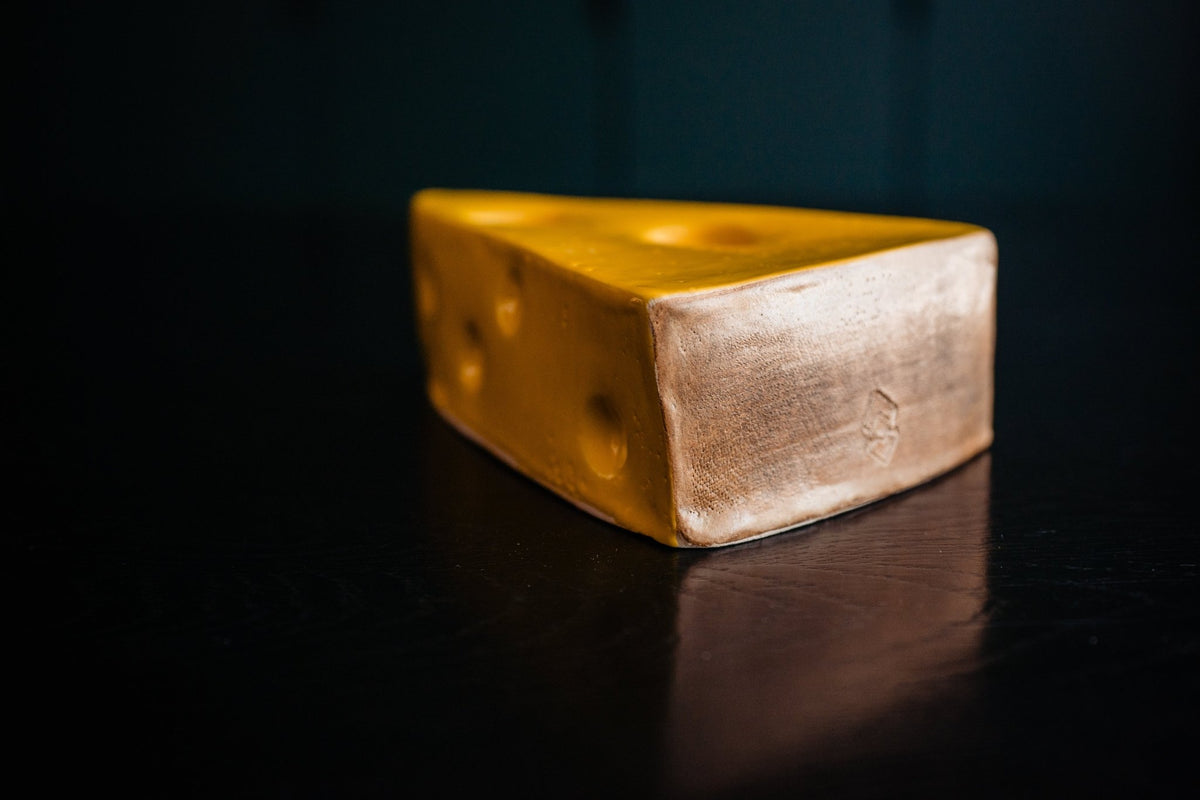 Gele keramieken kaaswig met uitsparingen in het bovenvlak voor dip.