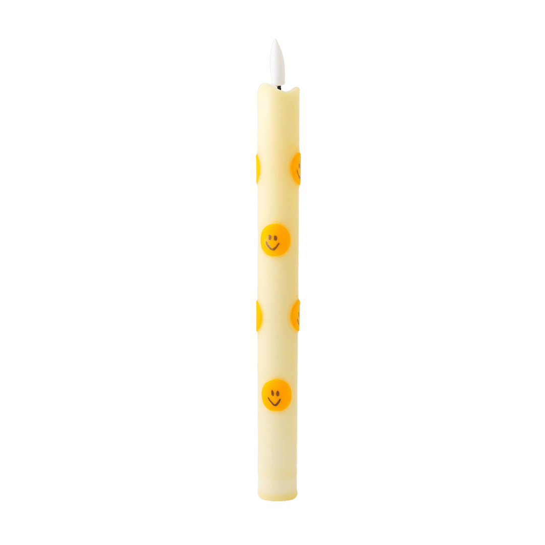 De slanke kaars heeft een zachte lichte tint en is versierd met opvallende oranje smileys, waardoor hij direct een positieve en eigentijdse uitstraling krijgt.