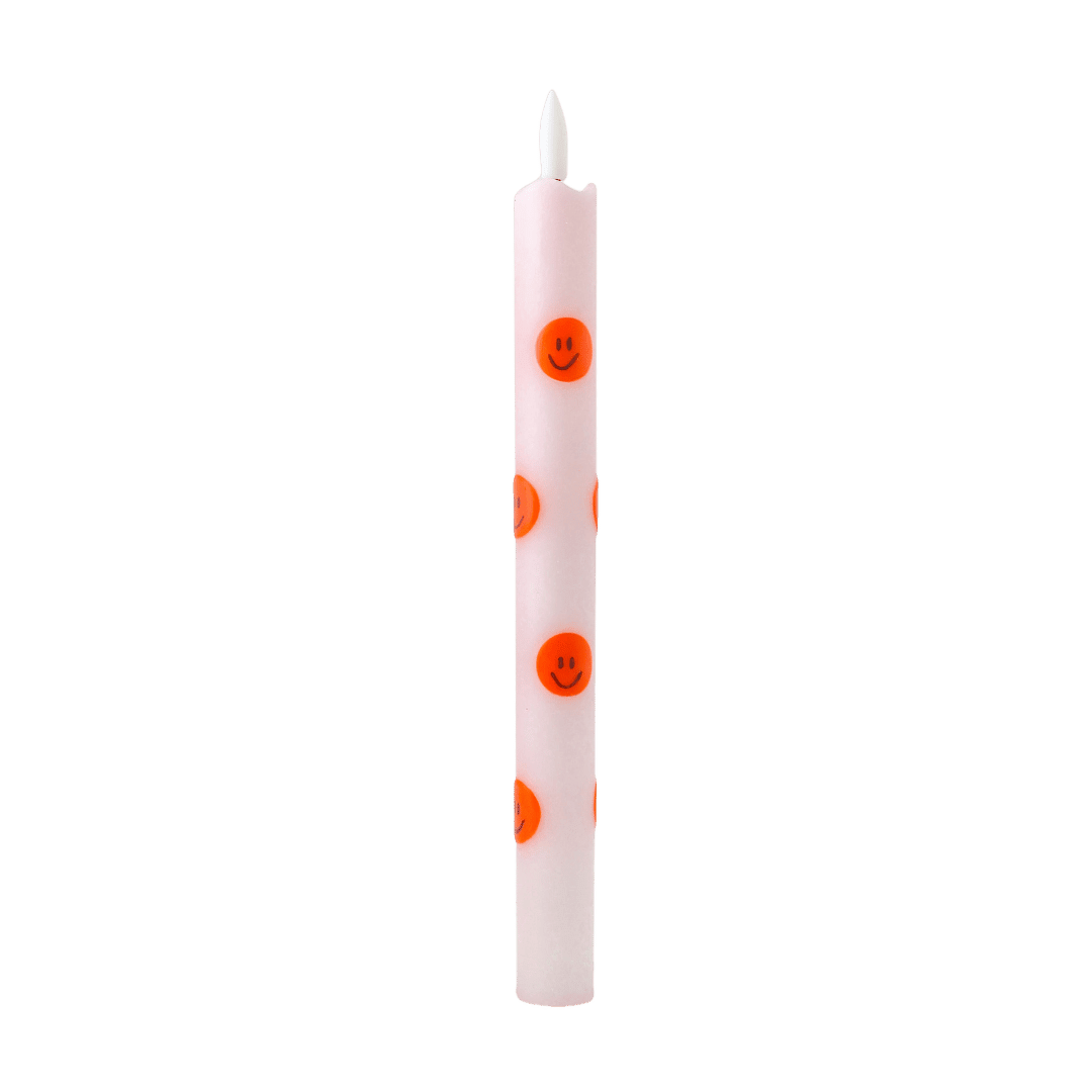  Deze vrolijke dinerkaars is uitgevoerd in een zachte lichtroze tint en versierd met speelse oranje smileys rondom. 