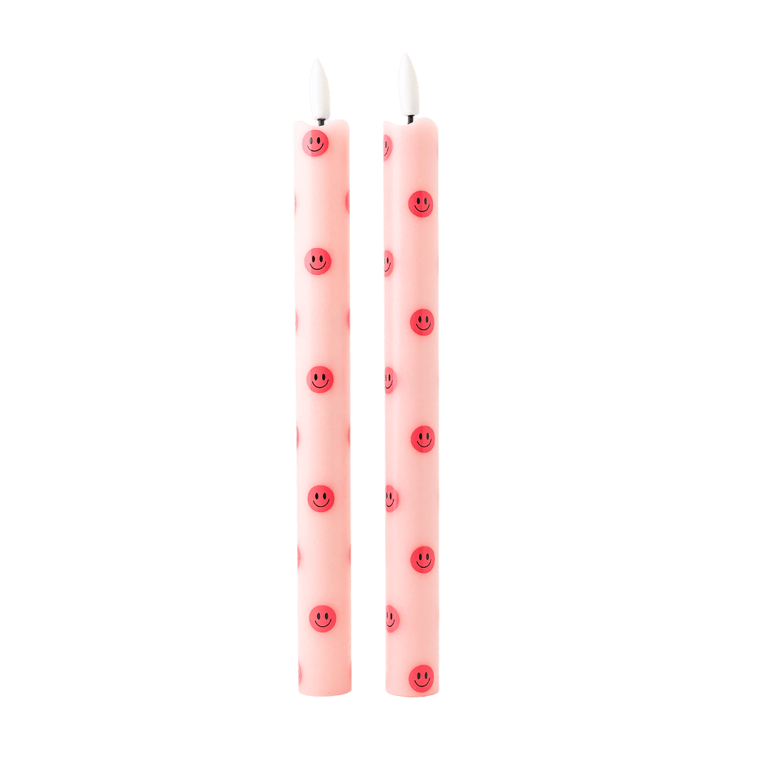 Deze speelse ledkaars combineert een zachte roze basis met vrolijke smiley-details