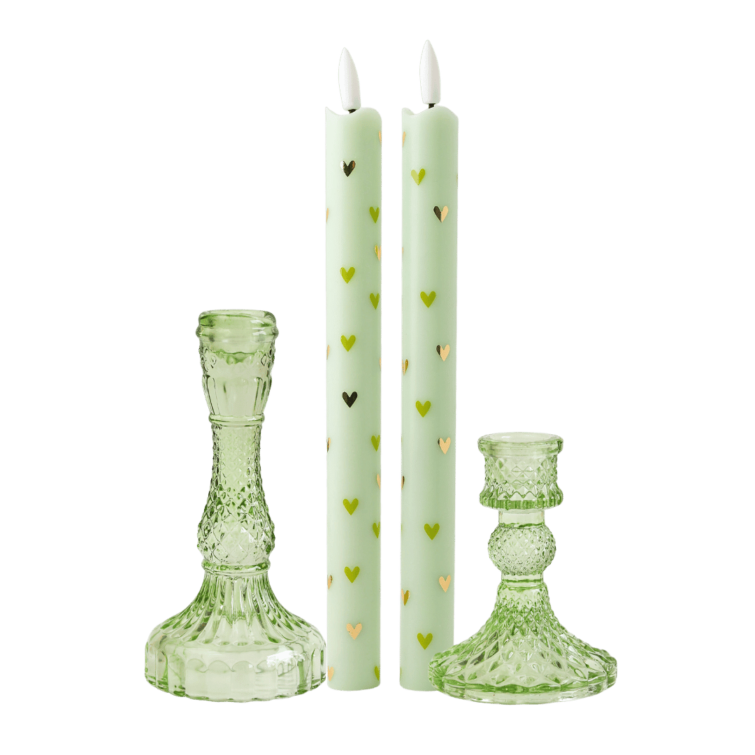  stijlvolle set bestaat uit twee ledkaarsen met subtiele groene en gouden hartjes, gecombineerd met twee elegante groene glazen kandelaren. 