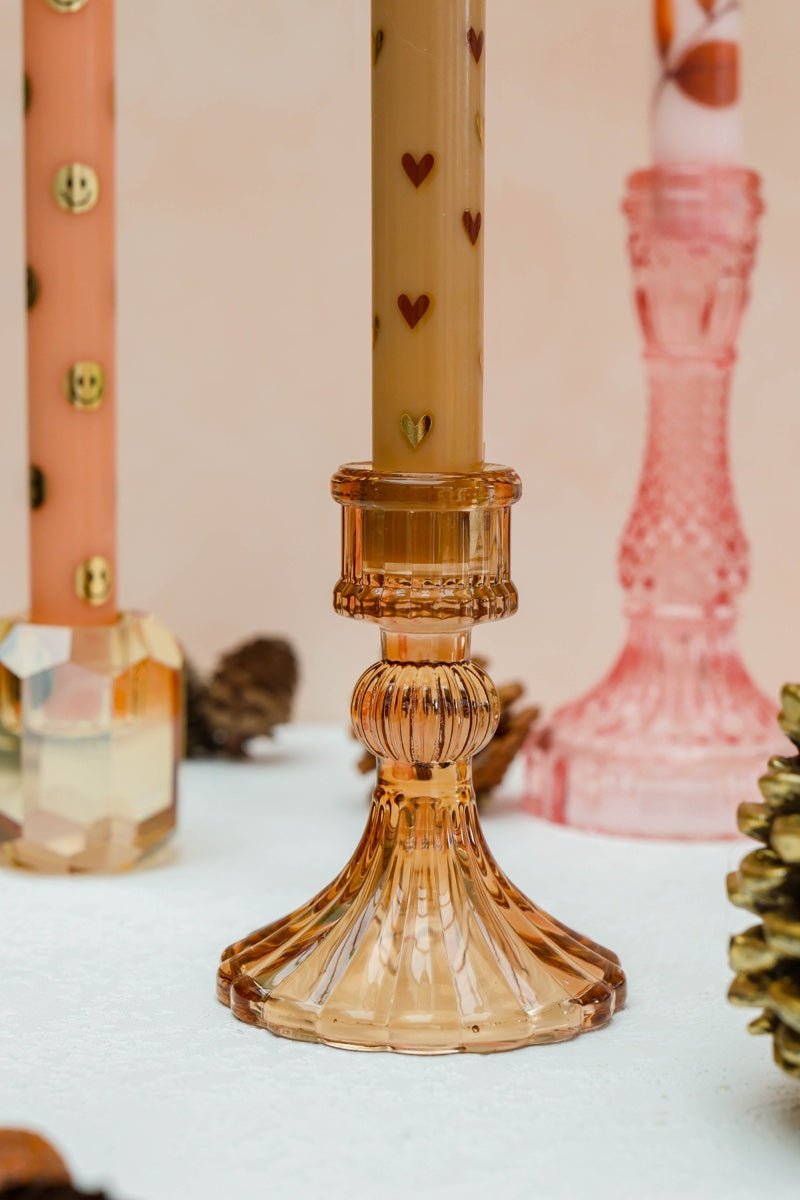 Bestaat uit twee zandkleurige ledkaarsen met subtiele hartjes en twee stijlvolle glazen kandelaren in roze en amberkleurig glas