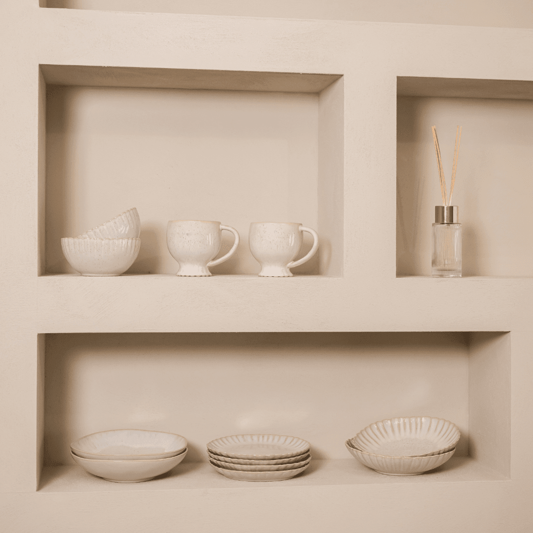 Gebroken wit servies in twee lichte wandnissen met een geurstokjesfles.