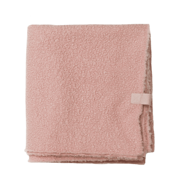 Opgevouwen plaid van oudroze bouclé met korrelige, teddyachtige structuur.