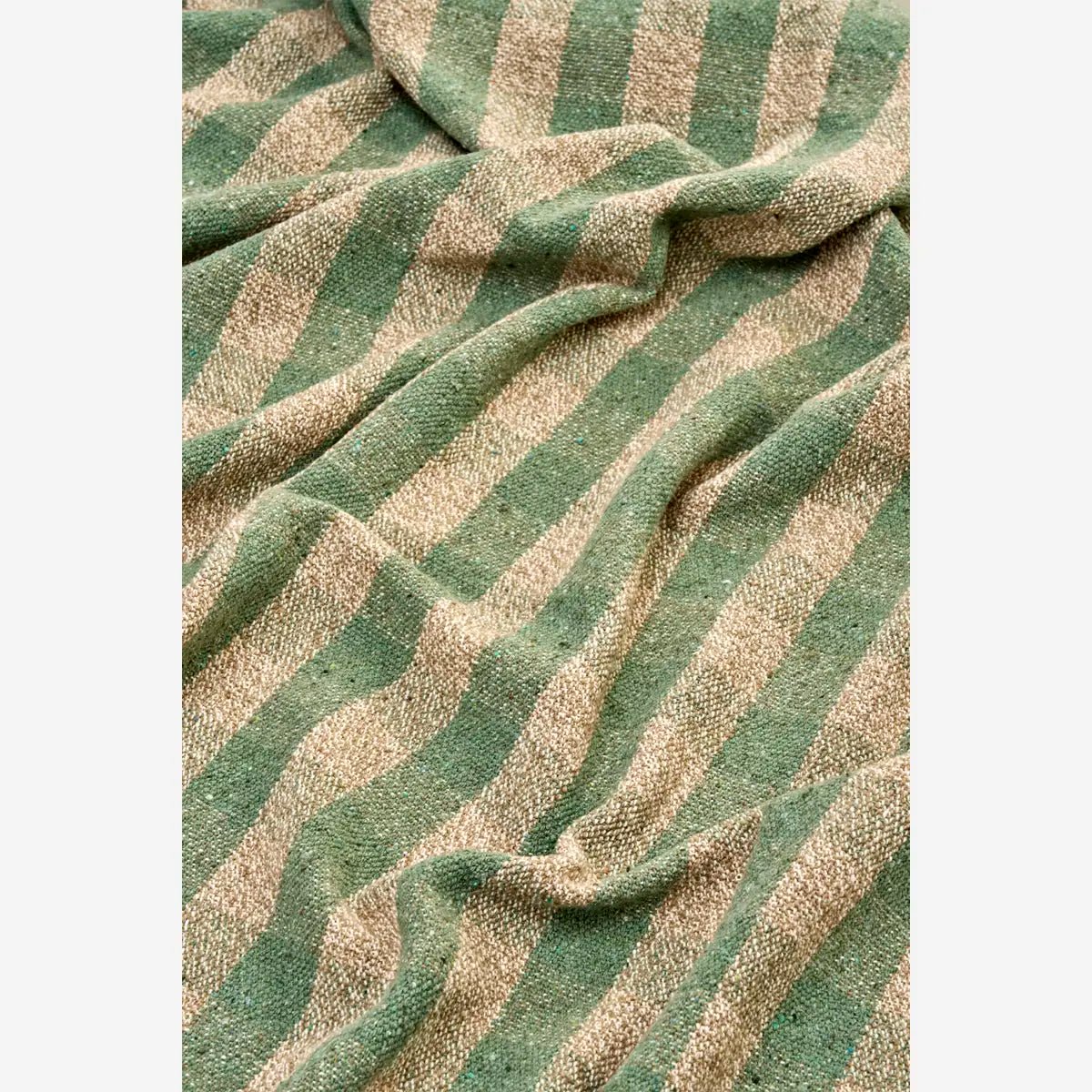 Het tijdloze streeppatroon in groen en beige geeft de plaid een rustige basis, terwijl de subtiele geweven structuur en decoratieve franjes zorgen voor een ambachtelijke uitstraling.