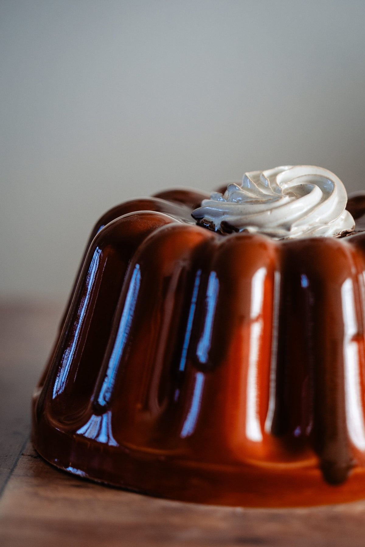 Detail van een keramieken pudding met glanzend roestbruin glazuur en een slagroomtoef.