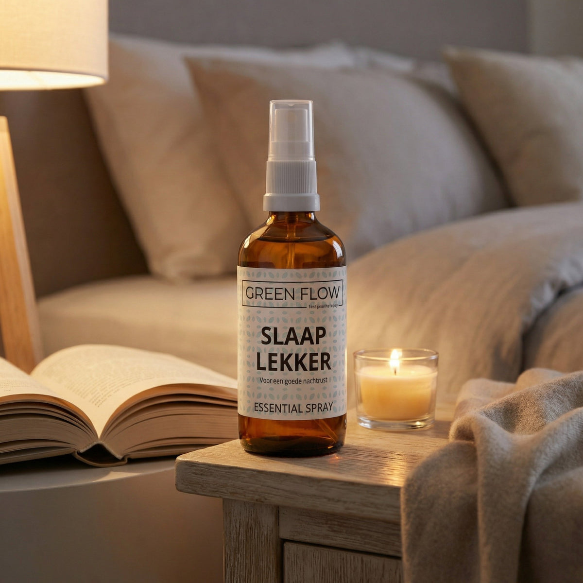 Bruin glazen verstuiver op een nachtkastje met een opengeslagen boek en een brandende kaars.