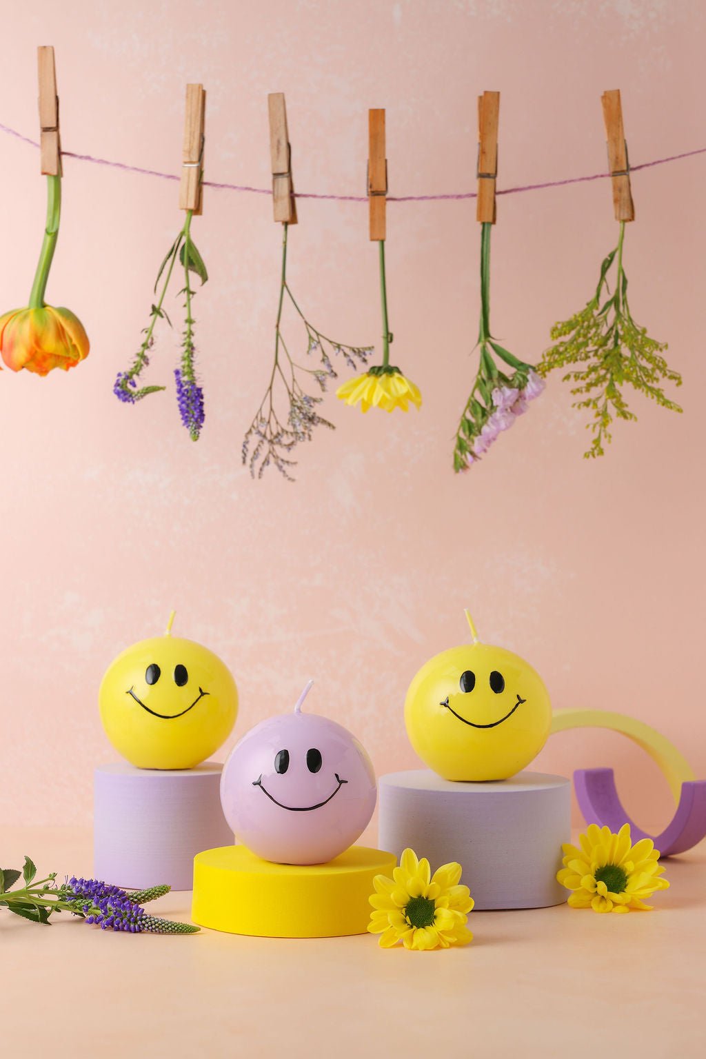Handgemaakte bolkaarsen paars rond met een zwart smiley gezicht erop.