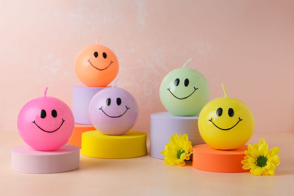 Handgemaakte bolkaarsen rond met een zwart smiley gezicht erop.