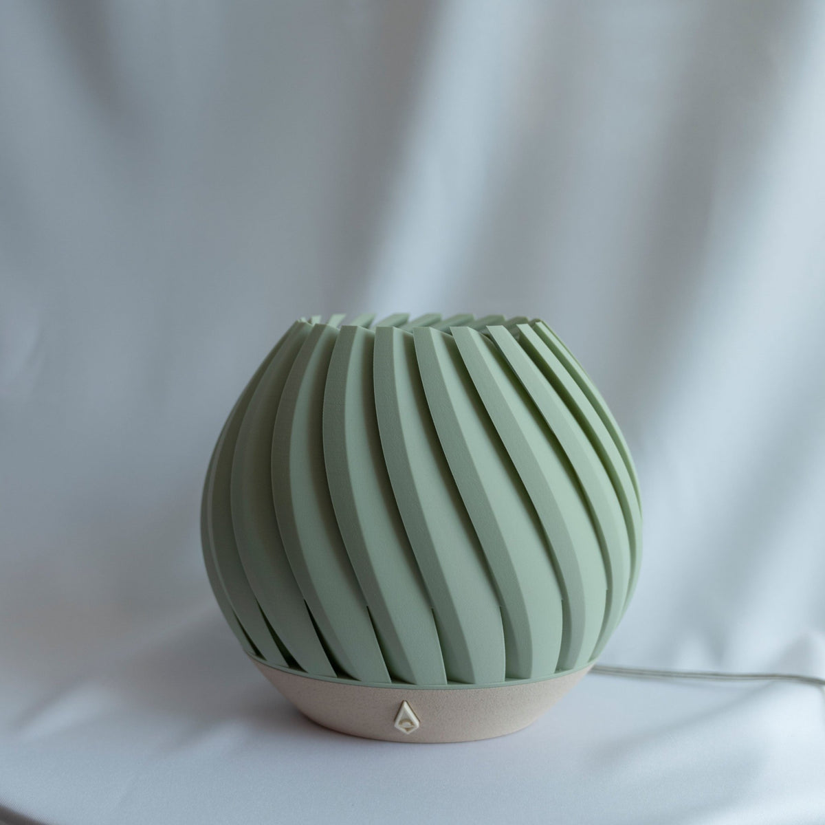 Zeegroene brede lampenkap van dichtbij met de geribbelde schelpvorm en de zandkleurige voet.
