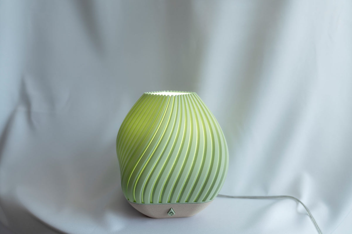 Groene geribbelde tafellamp van voren tegen een witte doek, met het snoer zichtbaar.