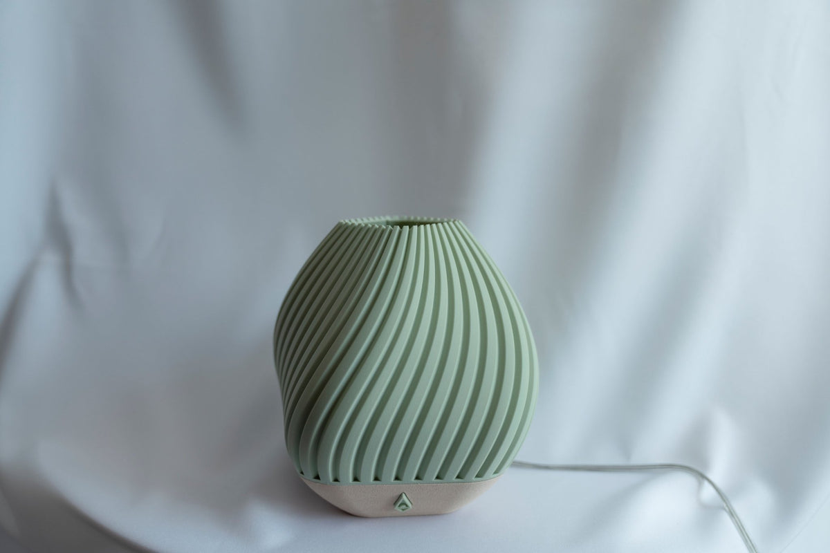 Groene geribbelde tafellamp met lichte voet tegen een witte doek, uitgeschakeld.