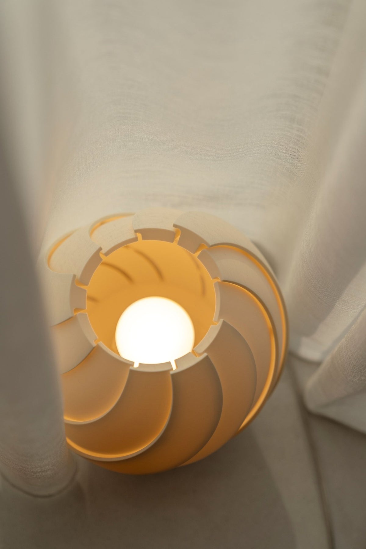 Brandende bolvormige lampenkap schuin van boven, met de gloeiende opening en de ledlamp zichtbaar.