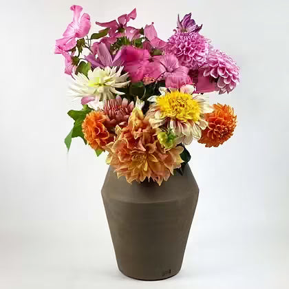 Chocoladebruine keramieken vaas met een kleurrijk boeket dahlia's.