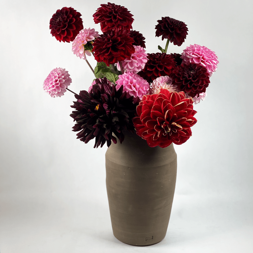 Chocoladebruine keramieken vaas met een boeket dahlia's.