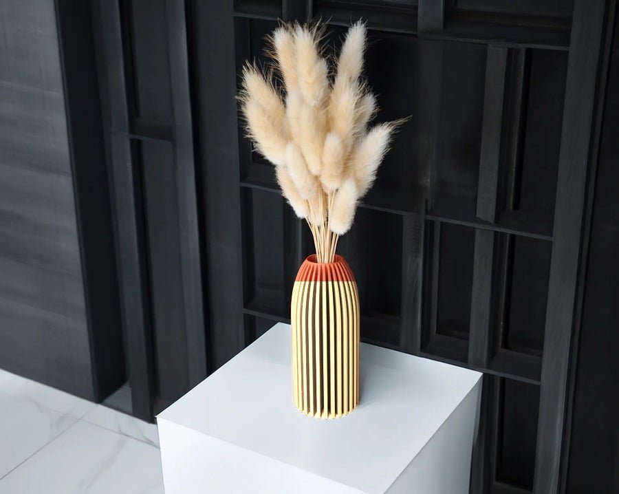 Slanke geribbelde vaas in camel met droogbloemen erin.