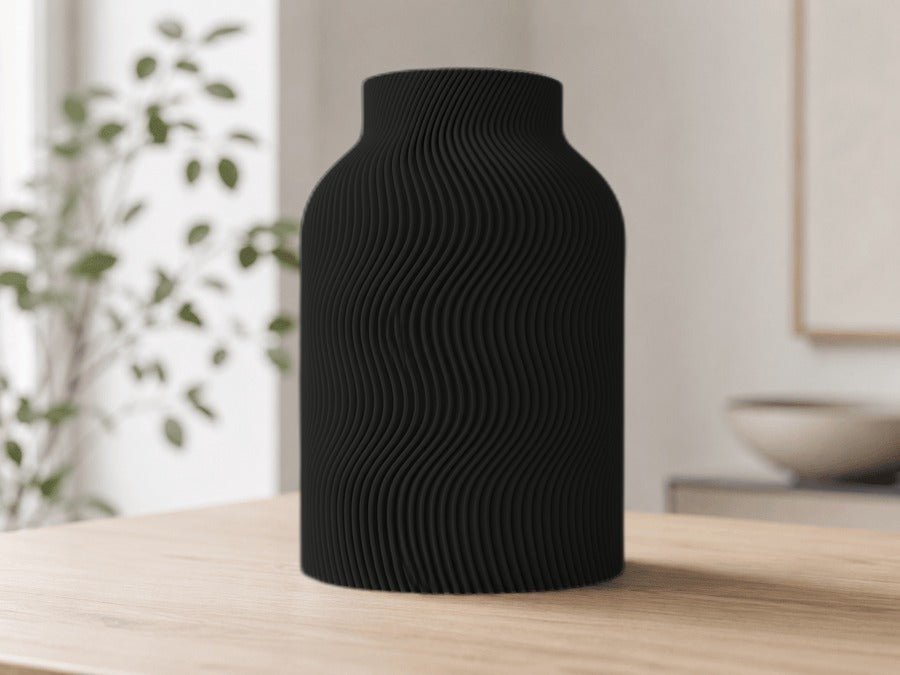 Vaas met golvende ribbels in mat zwart op een houten tafel.
