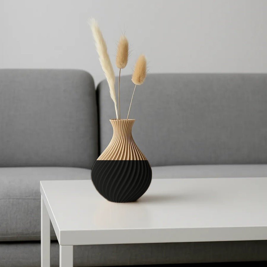 Vaas met gedraaide golvende ribbels in mat zwart, met droogbloemen erin.