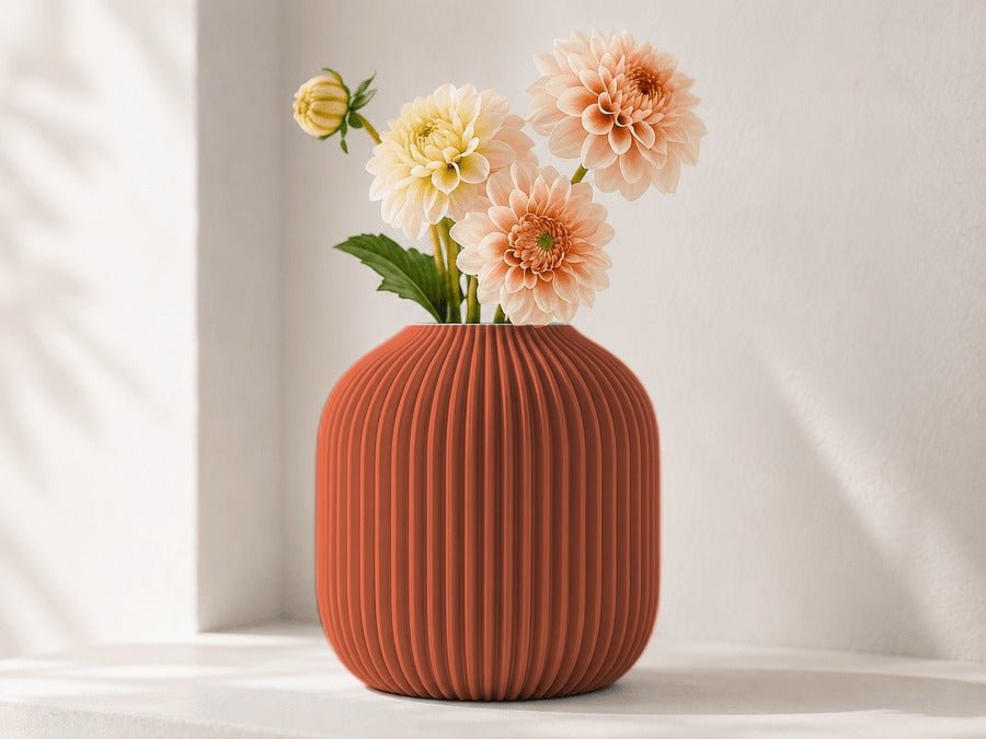 Ronde geribbelde vaas in terracotta met dahlia's erin.
