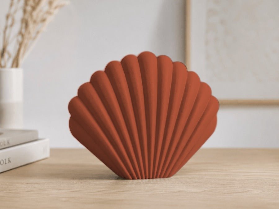 Waaiervormige schelpvaas met brede ribben in terracotta.