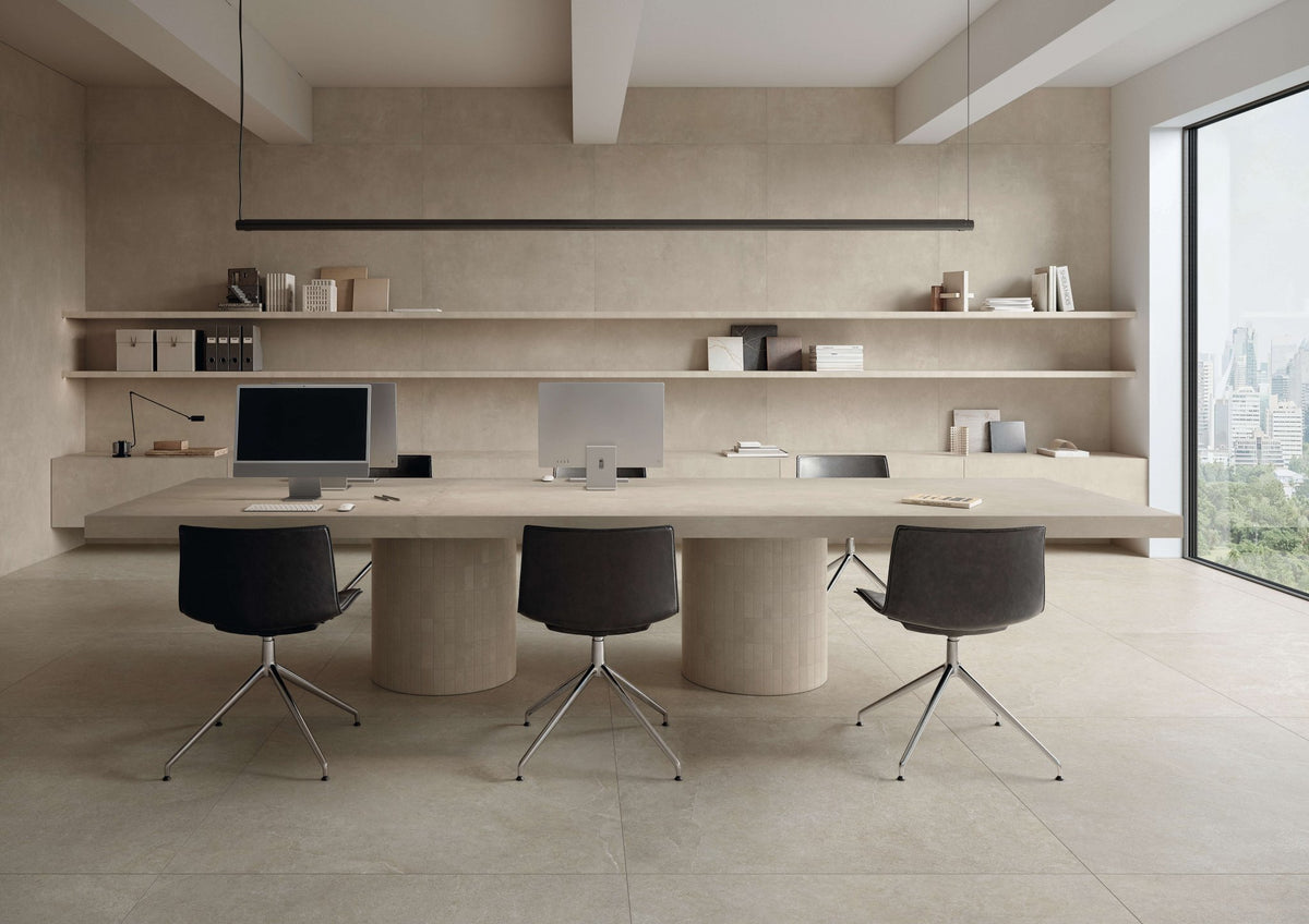 Kantoor met beige kalksteenlook vloer, ovale vergadertafel en zwarte stoelen.