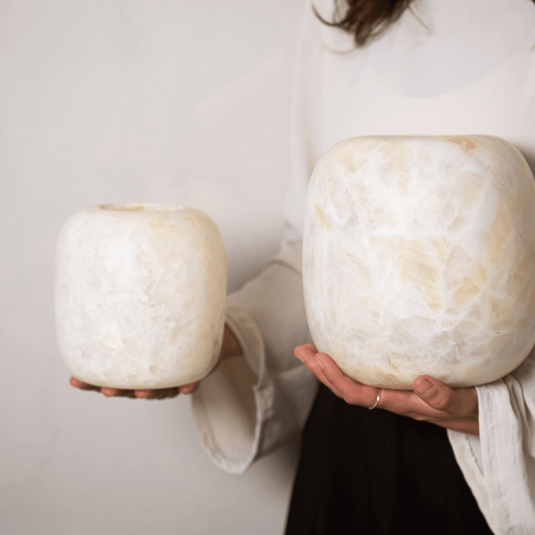 Grote en kleine albasten waxinelichthouder, de grootste met twee handen vastgehouden.